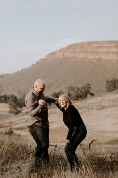 a man and woman standing in tall grass