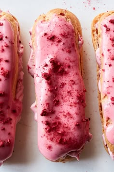 three doughnuts with pink icing and sprinkles on them