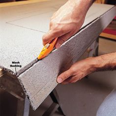 a man is measuring the width of a piece of concrete with a pair of scissors