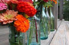 several vases filled with colorful flowers sitting on a wooden table outside in the sun