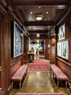 the hallway is lined with wooden paneling and ornately decorated rugs on either side