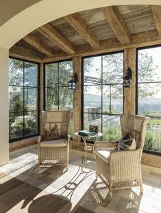 the sun shines through two large windows into an ocean view room with wicker furniture