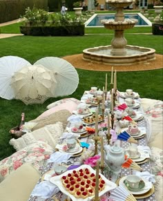 a table set up for a tea party with umbrellas in the background and plates on it