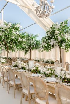 a table set up with white flowers and greenery on the tables for an event