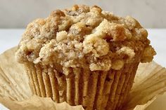 a muffin with crumbs sitting on top of a piece of parchment paper