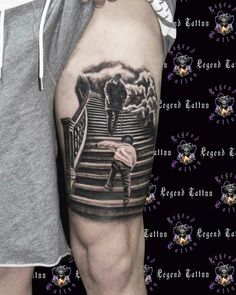 a man with a tattoo on his arm is standing in front of a stair case