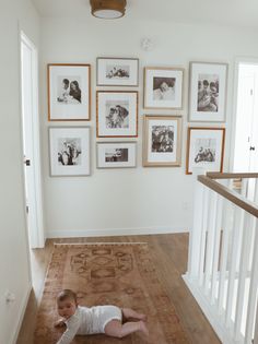 a baby laying on the floor in front of some pictures