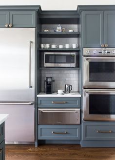 a kitchen with gray cabinets and stainless steel appliances