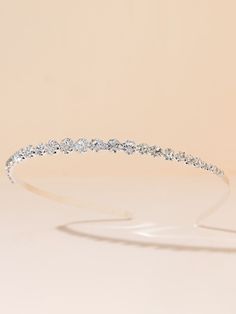 a white headband with crystal stones on the top and bottom, in front of a beige background