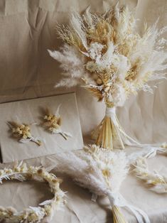 dried flowers and feathers are arranged on a sheet of white paper next to an envelope