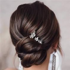 a woman with her hair in a low bun and some pearls on the back of her head