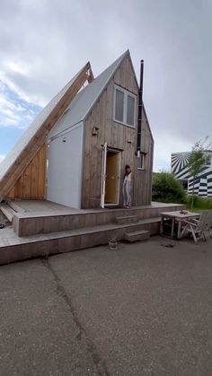 a man standing outside of a tiny house on top of concrete steps with a ramp leading up to the door