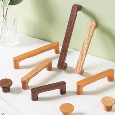 several wooden handles and knobs on a white table next to a vase with flowers