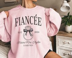 a woman wearing a pink sweatshirt with the word fancy on it