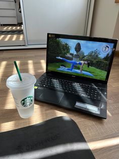 a laptop computer sitting on top of a wooden table next to a cup of coffee