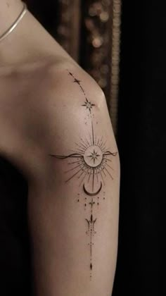 a woman's arm with a sun and stars tattoo on the left side of her shoulder