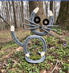 a cat statue in the woods with eyes and ears on it's head, made out of plastic pipes