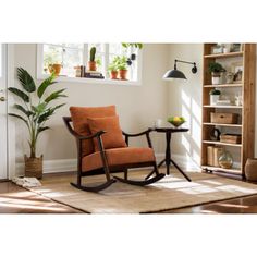 a rocking chair in front of a window with potted plants on the side table