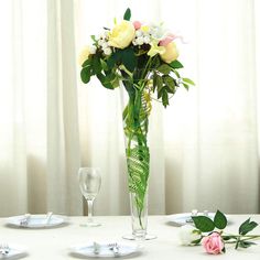 a vase filled with flowers sitting on top of a table next to two empty wine glasses