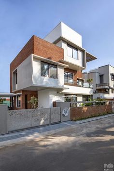 a modern house with brick and concrete walls on the side of a street in front of a fence