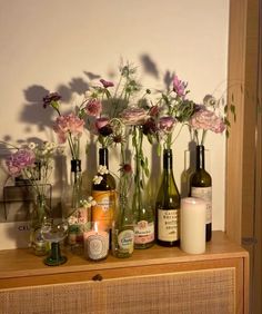 flowers and candles are arranged in vases on a dresser