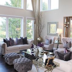 a living room filled with lots of furniture next to large windows on top of a hard wood floor