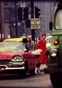 two people crossing the street in front of cars