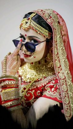 a woman with makeup on her face and wearing a red veil, gold headdress and sunglasses