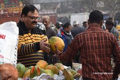 a man is holding some fruit in his hand and looking at it while people stand around him