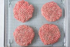 three hamburger patties on a baking tray ready to be cooked in the oven or baked