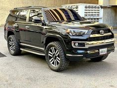 a black toyota 4runner is parked in front of a building with its hood up