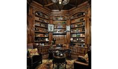 a room filled with lots of wooden shelves and chairs next to a table in front of a book shelf