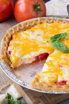 a pie with cheese and tomatoes in the background