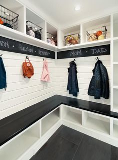 an organized mud room with coats hanging on the wall and chalk writing on the walls