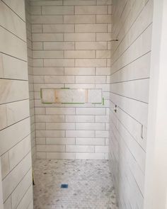 a white tiled shower stall with no curtain on the side and two green bars in the corner