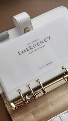 an empty emergency binder on top of a white purse with gold handles and metal clips