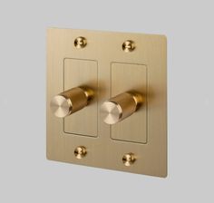 two dimmers are on the side of a metal wall plate with gold knobs