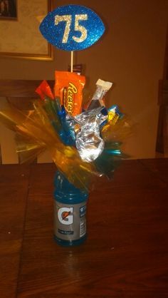 an arrangement of candy and candies in a football themed vase with the number 75 on it