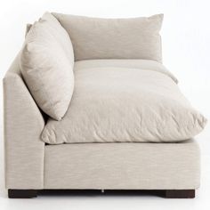 a white couch with two pillows on it's back and one arm folded up