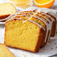 slices of orange pound cake with icing on white paper next to sliced oranges