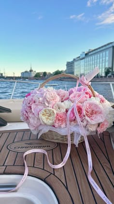 pink and white flowers in a basket on a boat