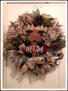 a wreath with the words welcome to living design on it and pine cones in the center