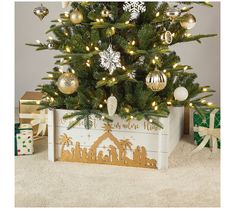 a small christmas tree in a wooden box with lights and ornaments on it, next to presents