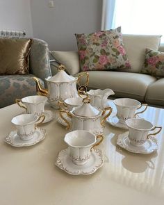 a table topped with lots of white and gold cups and saucers on top of it