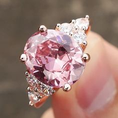 someone is holding a pink diamond ring with three stones on the top and bottom side