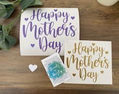 two mothers day cards sitting on top of a wooden table