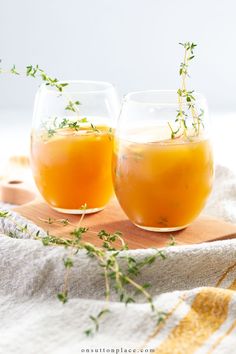 two glasses filled with orange juice on top of a wooden tray