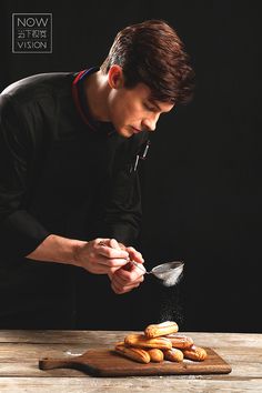 a man is sprinkling sugar on pastries with a spatula while standing in front of a cutting board