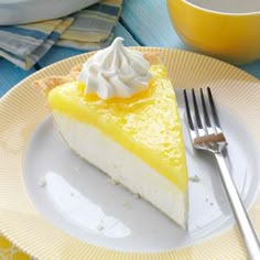 a slice of lemon pie on a yellow and white plate with a fork next to it