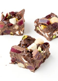 three pieces of chocolate dessert with nuts and other toppings